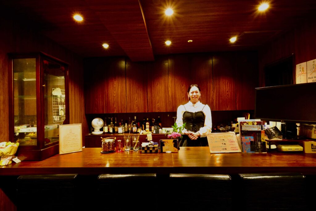 Cafe & Bar おぱぁるの店内。5席あるカウンター席とカウンター内にあさみママがいる。